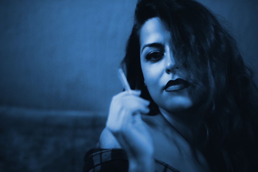 A deep-blue duotone of a woman smoking a cigarette.